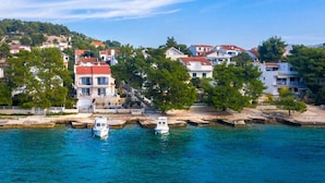 A coastal town with buildings along the waterfront, a dock with boats, and a hillside in the background.