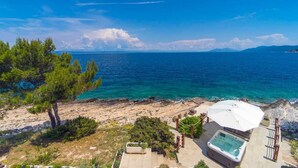 A coastal property with a hot tub, outdoor seating, and a view of the sea.