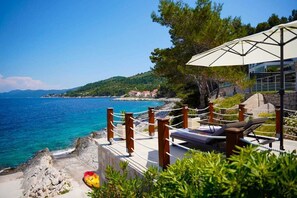 Un hôtel situé sur la côte, doté d’un salon avec vue sur la mer, d’une plage rocheuse et offrant un panorama sur le paysage environnant.