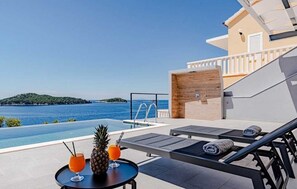 A rooftop pool area with lounge chairs, a table with drinks, and a view of the sea. - Villa Evia | Adriatic Luxury Villas (Blato)