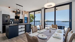 A modern kitchen with a central island, large windows, and a dining area with a view of the sea. - Villa Evia | Adriatic Luxury Villas (Blato)