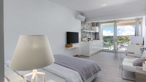 A modern bedroom with a bed, a TV, a desk, and a balcony with a view.