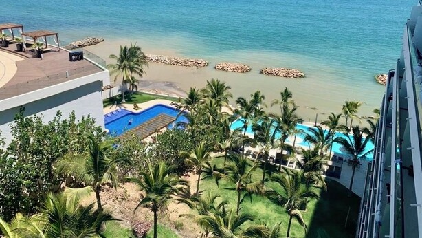 Un resort con piscina, palmeras y vista al océano.