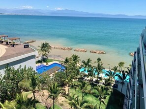 A resort with a pool, palm trees, and a view of the ocean. - Apartamento 305 Narval (Bucerías)