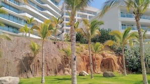 Un resort con césped, palmeras y un acantilado rocoso.