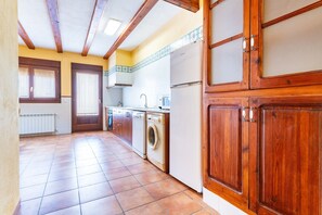 Une cuisine avec des meubles de rangement en bois, un lave-linge et un réfrigérateur.