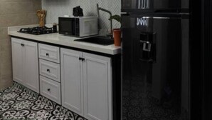 A modern kitchen with white cabinets, a black refrigerator, a microwave, and a gas stove. - Espectacular Apartaestudio Harry Potter (Santa Rosa de Cabal)