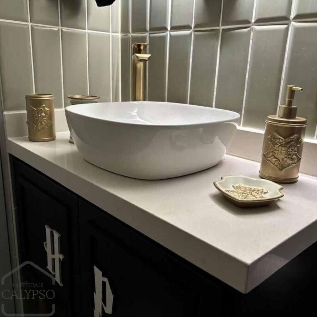 A bathroom with a white sink, a gold faucet, a beige soap dispenser, and a small beige dish.