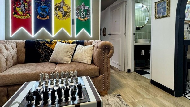 A living room with a chessboard, a sofa, and a wall with four illuminated banners. - Espectacular Apartaestudio Harry Potter (Santa Rosa de Cabal)