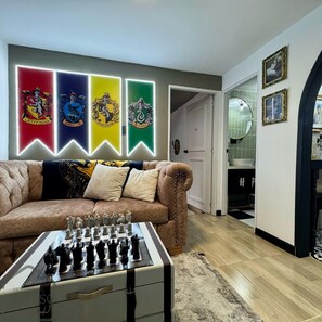A living room with a chessboard, a sofa, and a wall with four illuminated banners. - Espectacular Apartaestudio Harry Potter (Santa Rosa de Cabal)