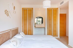 A bedroom with a bed, wooden wardrobe, and a mirror.