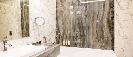 A modern bathroom with a marble vanity, a large mirror, a bathtub, and a shower area.