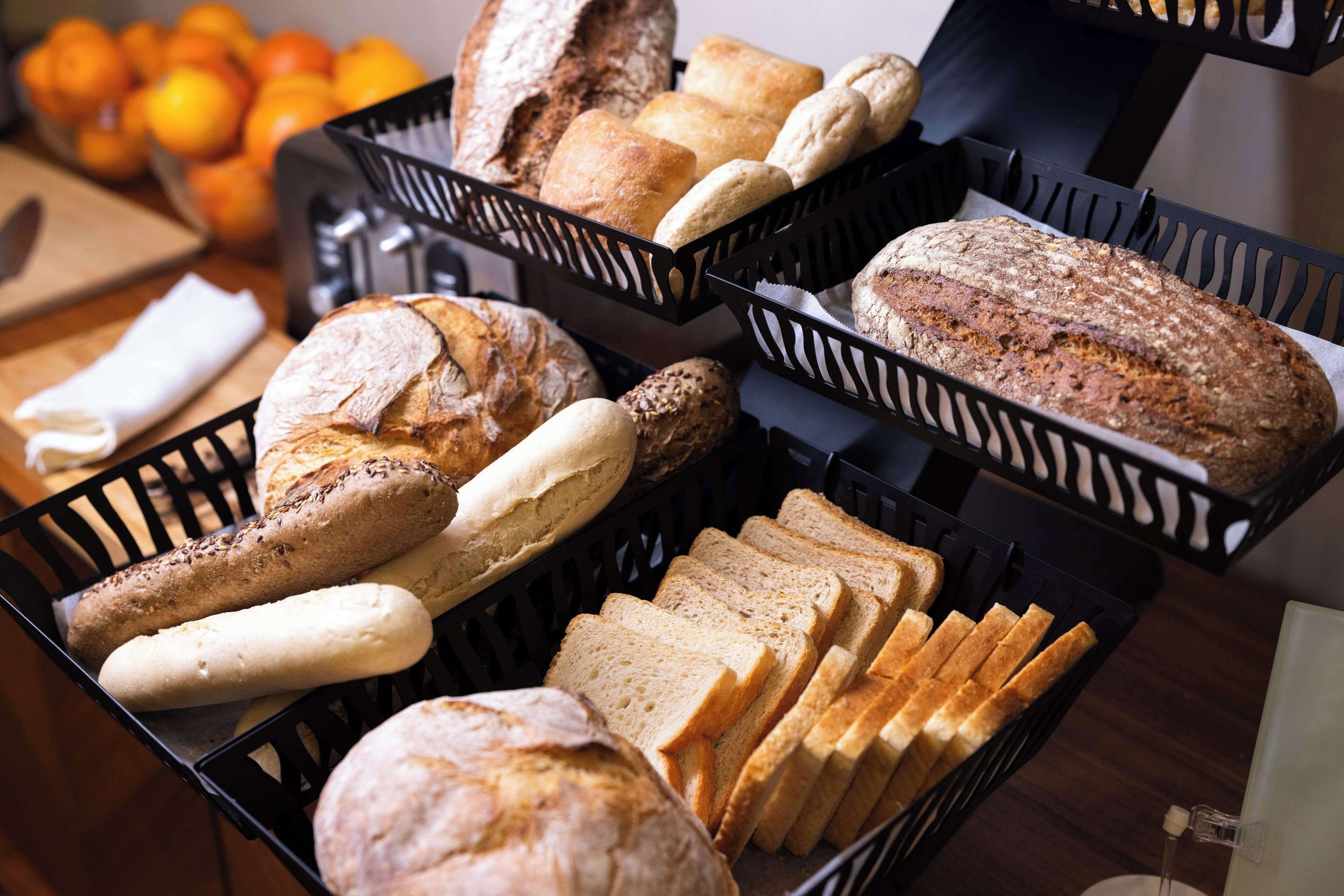 A variety of breads and pastries in black baskets on a table.