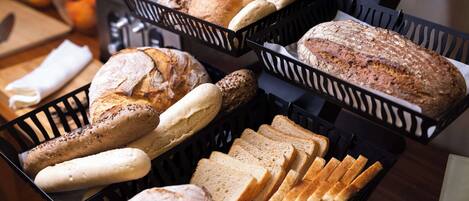 A variety of breads and pastries in black baskets on a table.