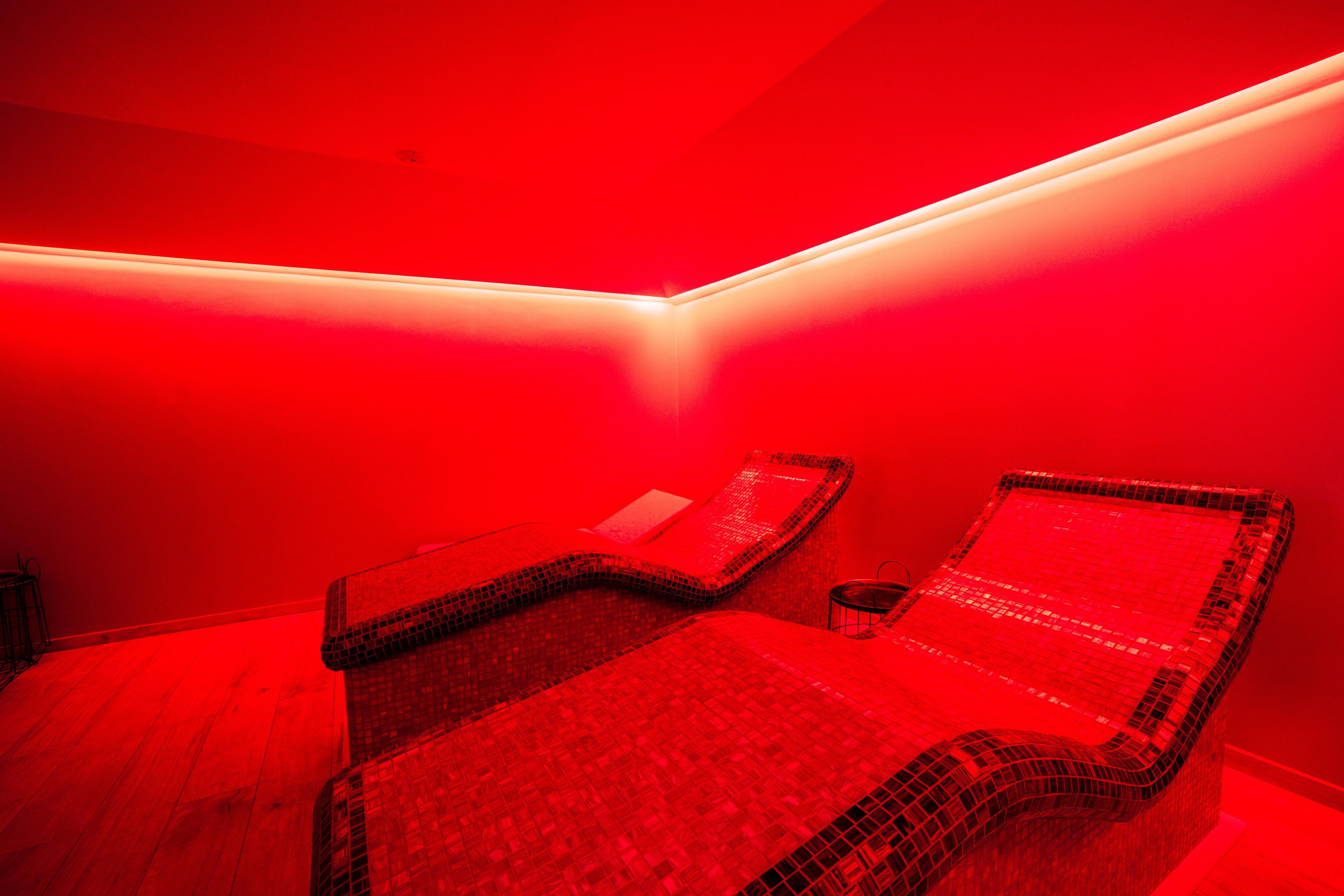 A room with two massage chairs, a small table, and a wall-mounted light fixture.