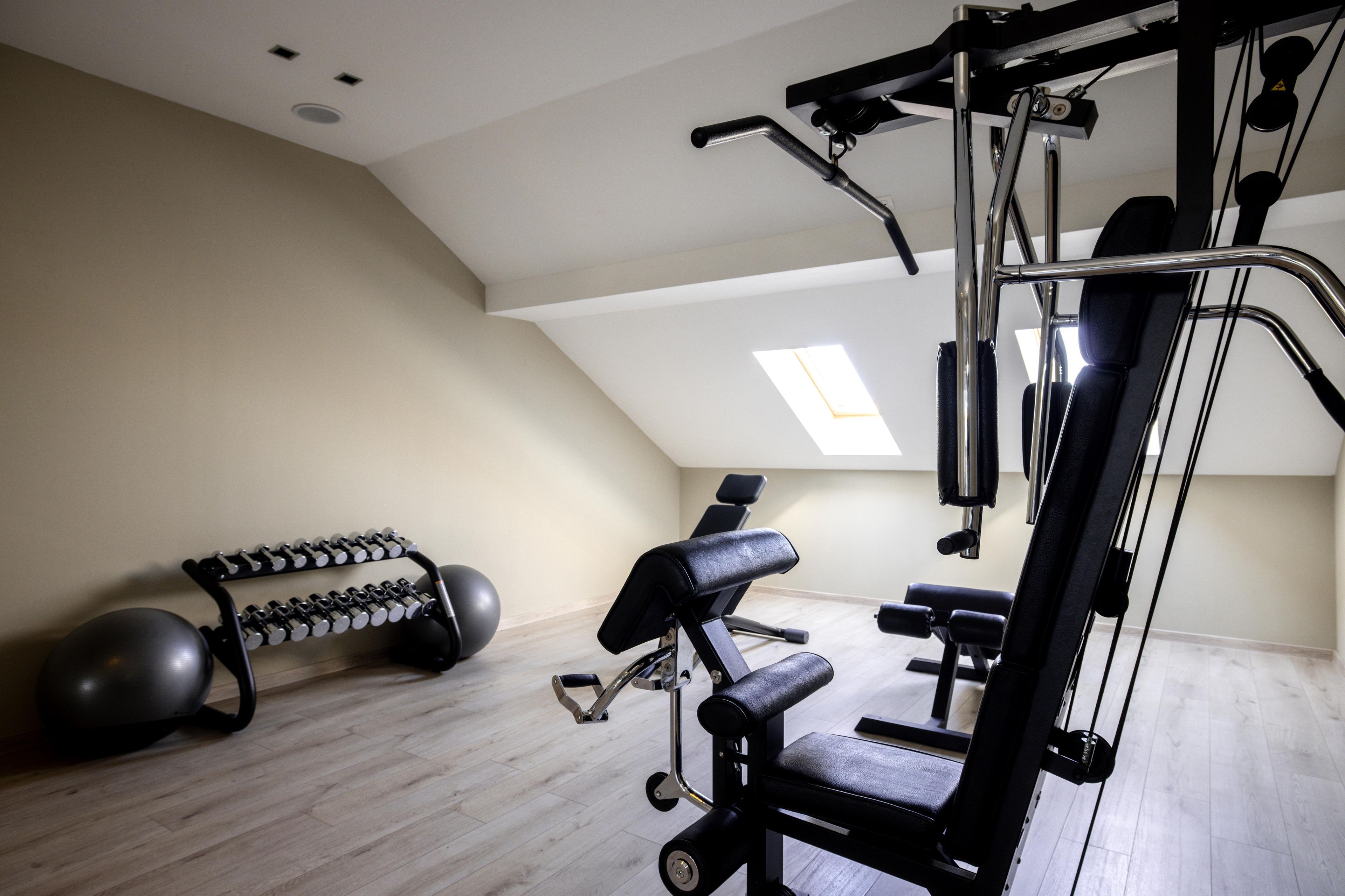 A gym with exercise equipment, a bench, and a dumbbell rack.
