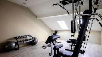 A gym with exercise equipment, a bench, and a dumbbell rack.