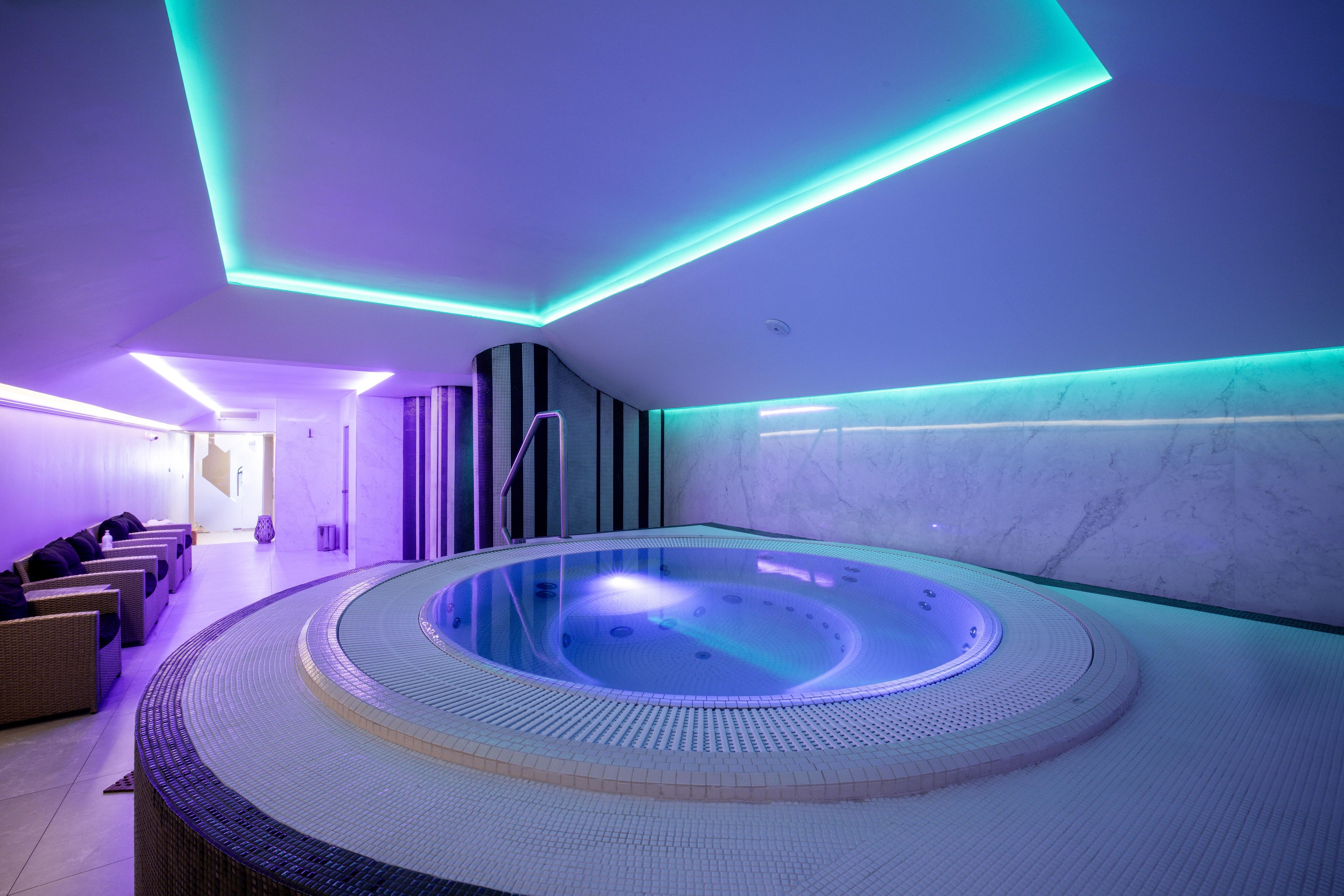 A spa with a circular hot tub, seating area, and modern lighting.