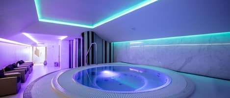 Un spa con una bañera de hidromasaje circular, zona de estar e iluminación moderna.