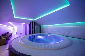 Um spa com banheira de hidromassagem circular, área de estar e iluminação moderna.