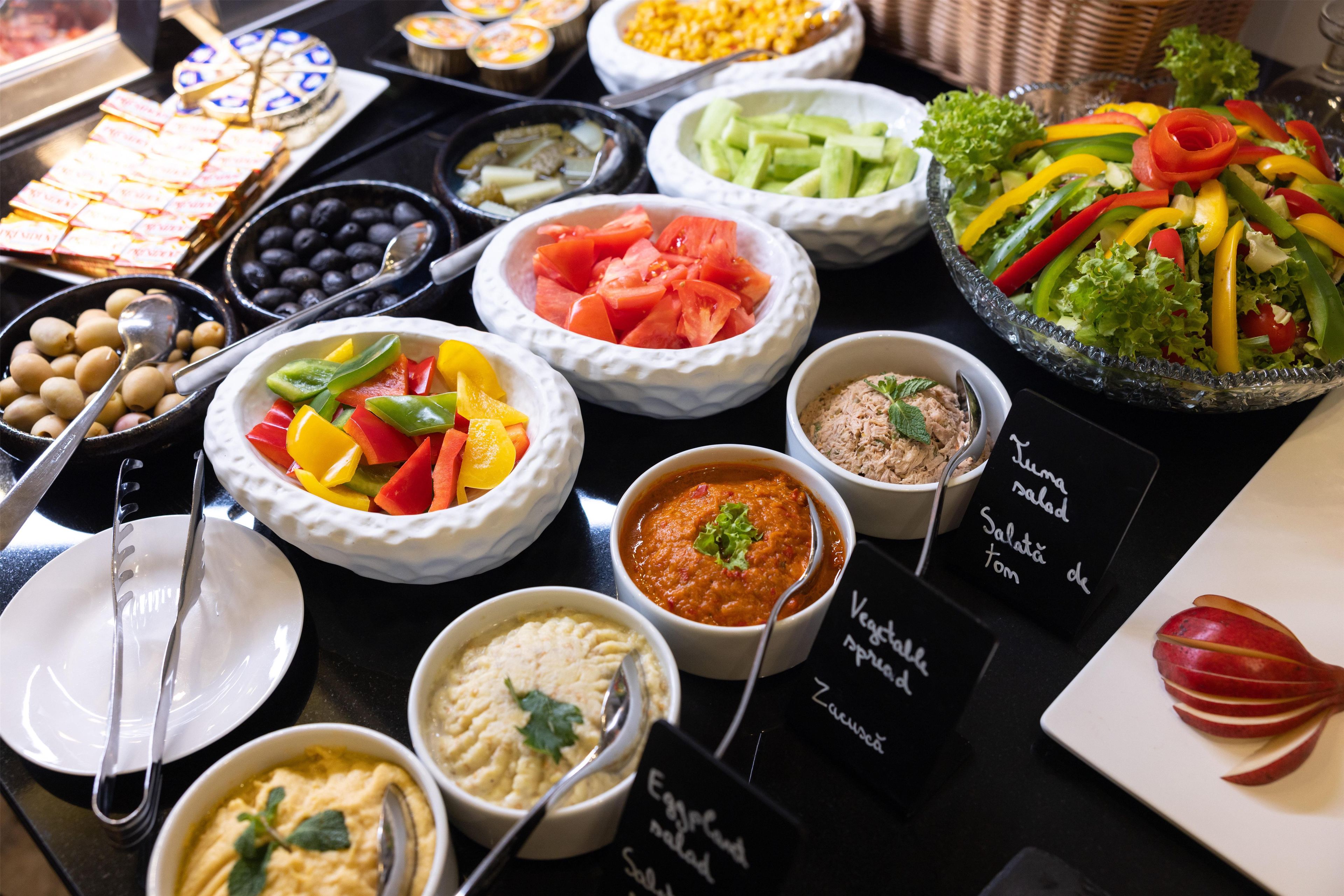 A buffet table with various food options including salads, dips, and a fruit display.