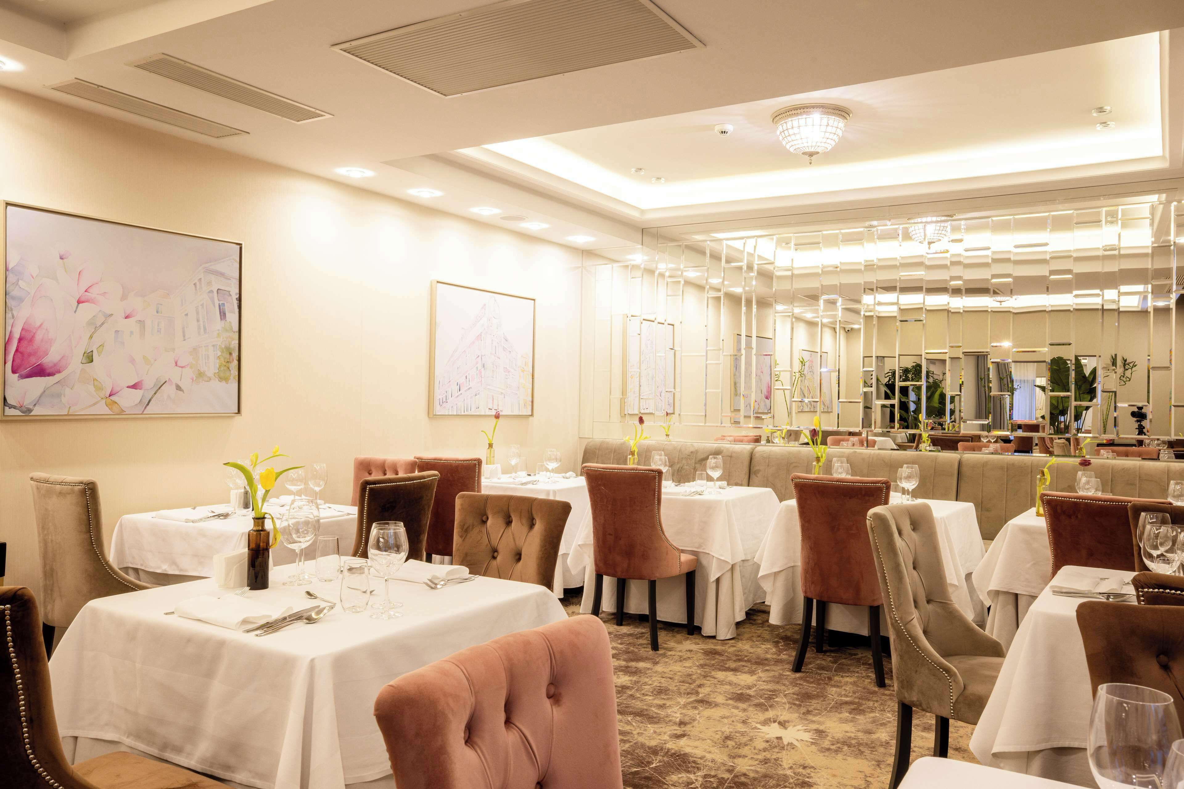 A dining area with multiple tables and chairs, white tablecloths, and floral centerpieces.