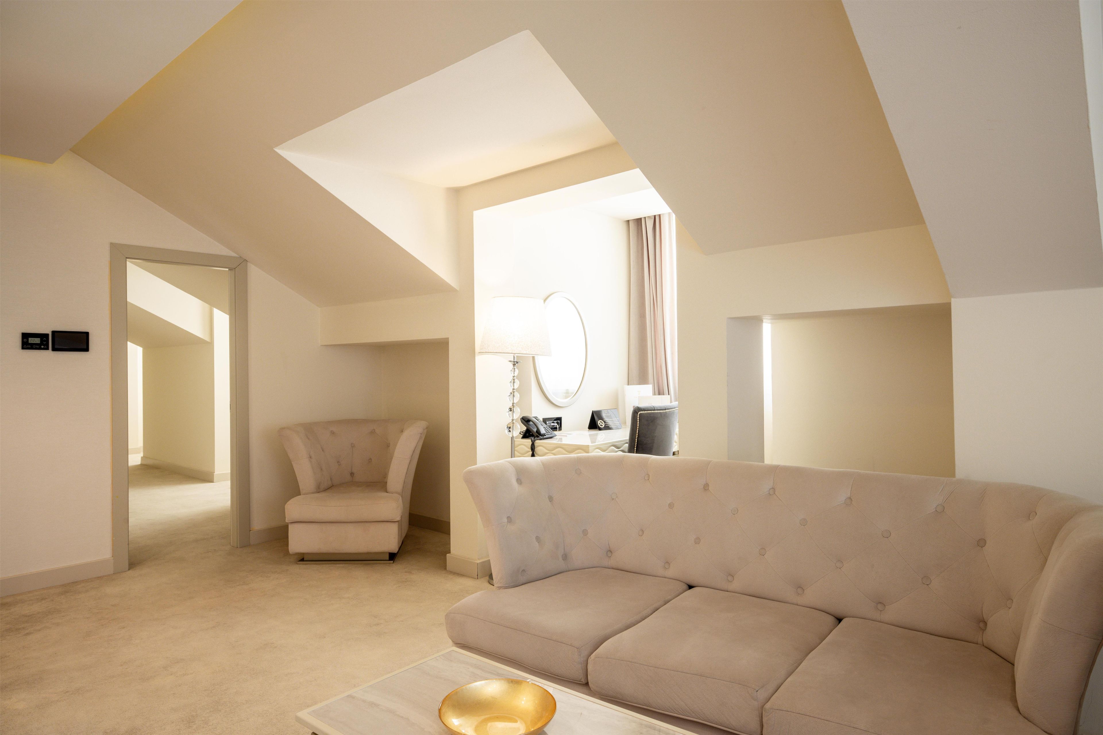 Un salon moderne avec un canapé, un fauteuil, une lampe et un miroir.
