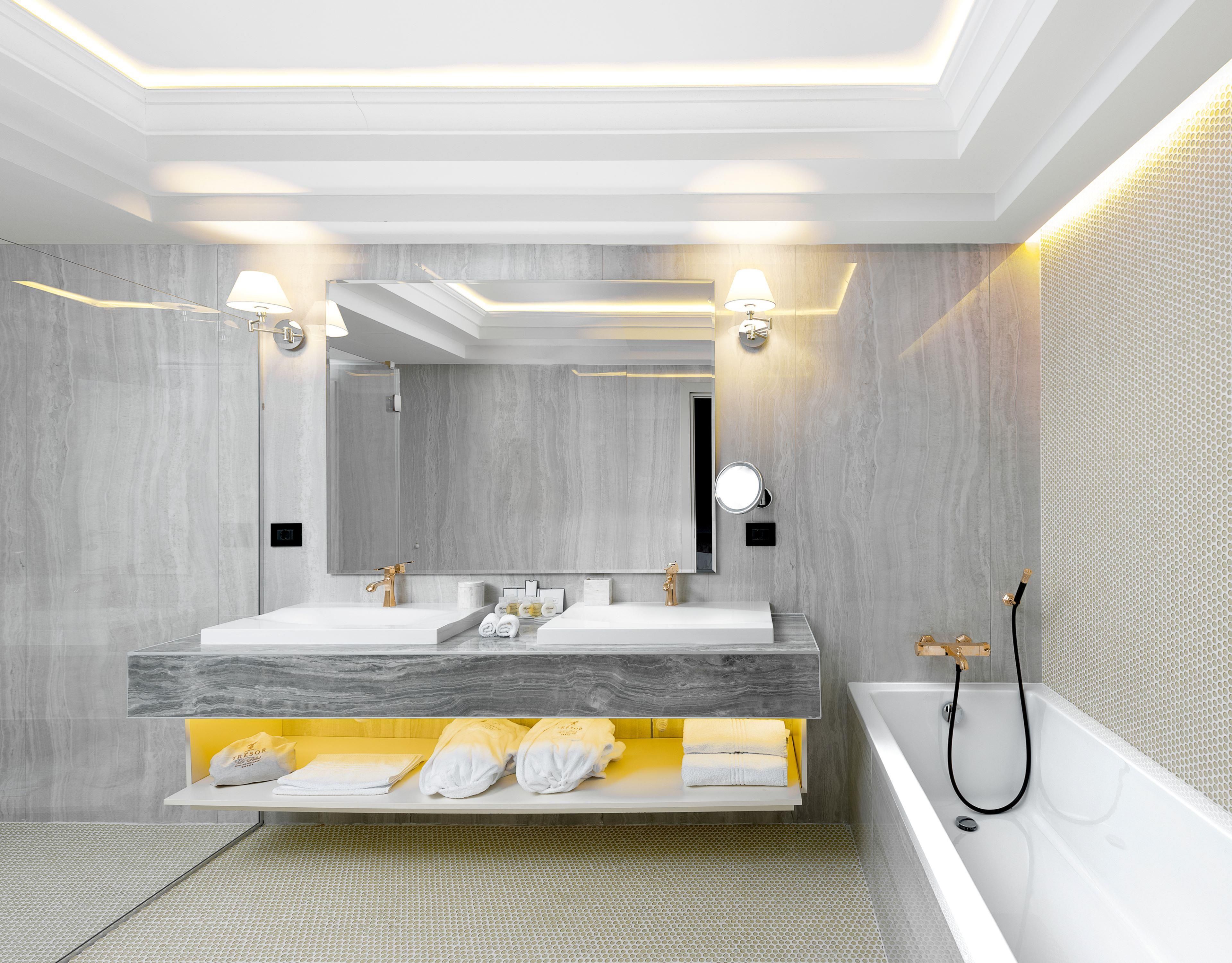 Un baño moderno con un espejo grande, lavamanos dobles y una bañera.