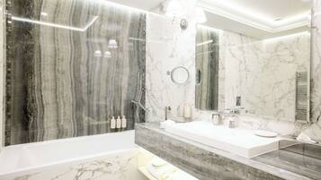 Un baño moderno con tocador de mármol, bañera y un espejo grande.