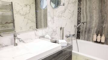 A modern bathroom with two sinks, a large mirror, and a bathtub.