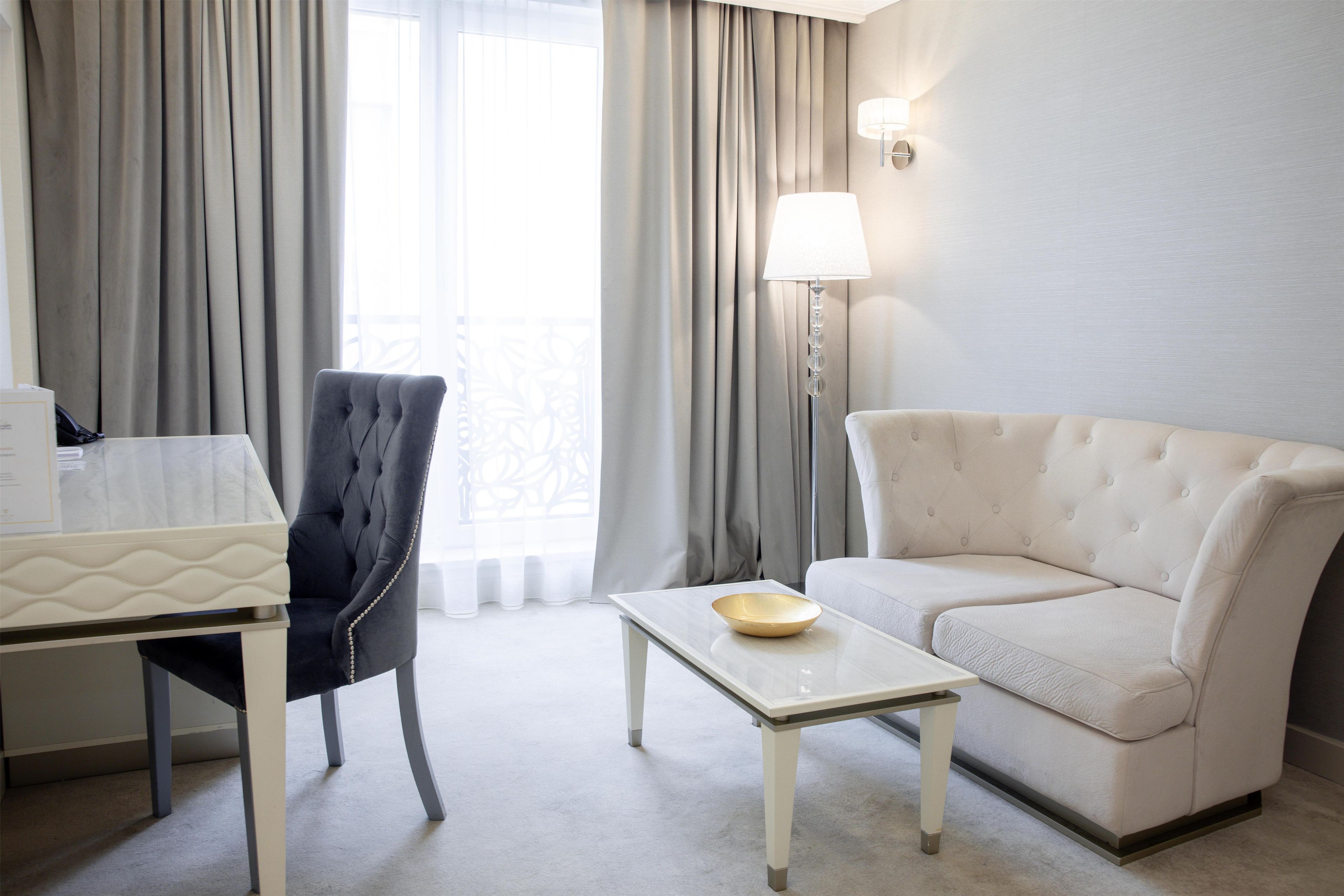 Ein Hotelzimmer mit einem Bett, einem Schreibtisch, einem Sessel, einer Couch und einer Lampe.
