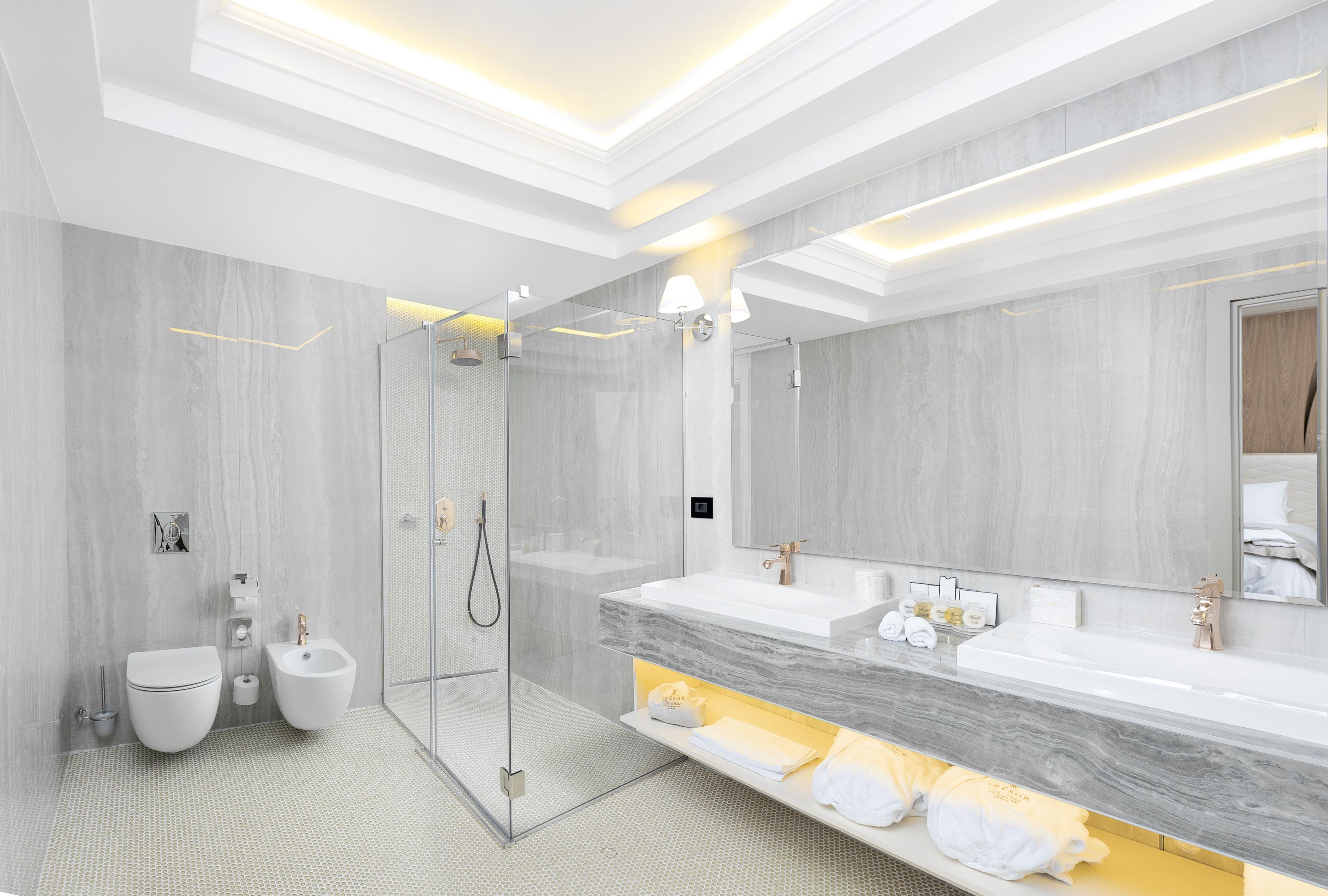 Ein modernes Badezimmer mit begehbarer Dusche, zwei Waschbecken und einem großen Spiegel.