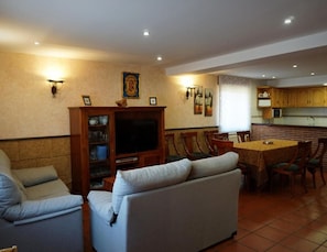 A living room with a sofa, TV, and dining area with chairs and a table. - Country House 'La Casa Nueva' with Private Terrace, Wi-Fi and Air Conditioning (Abejar)