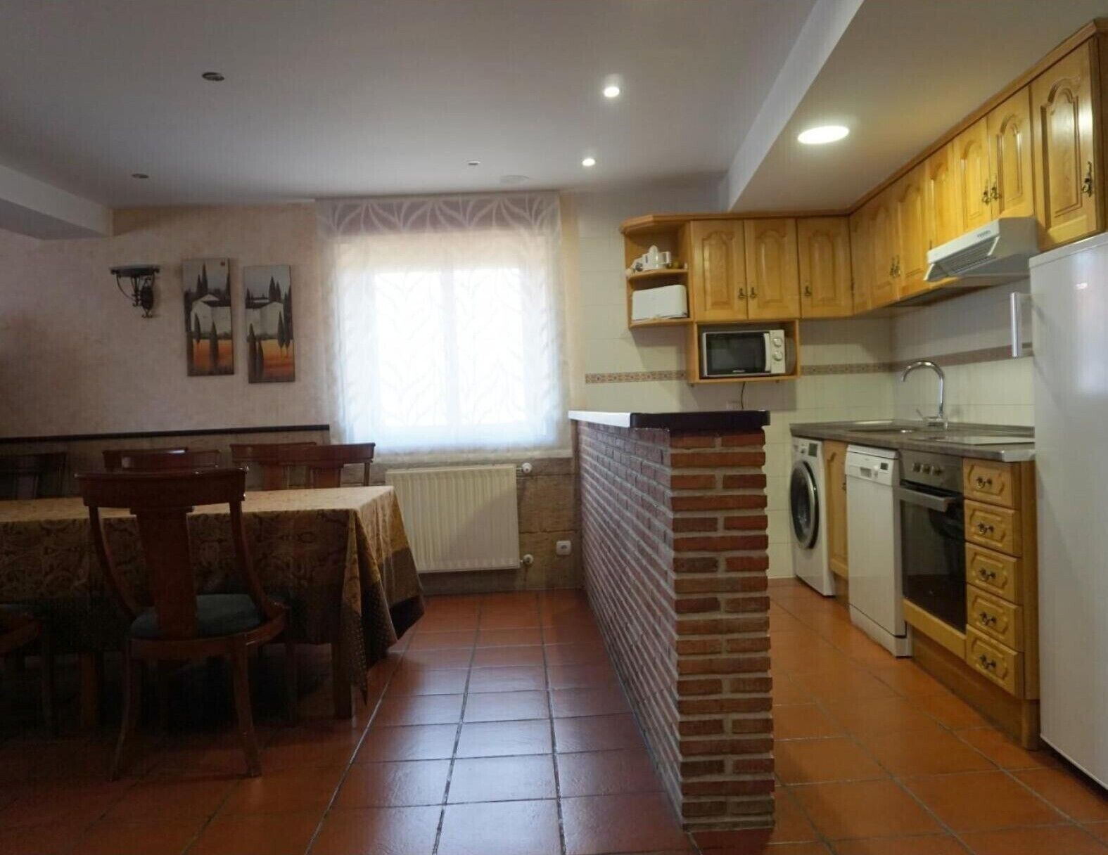 Cocina compacta con comedor, lavadora y microondas.