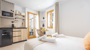 A hotel room with a bed, a kitchenette, a dining area, and a view through the door. - Room 'Altea  01' with Shared Pool, Wi-Fi and Air Conditioning (Altea)