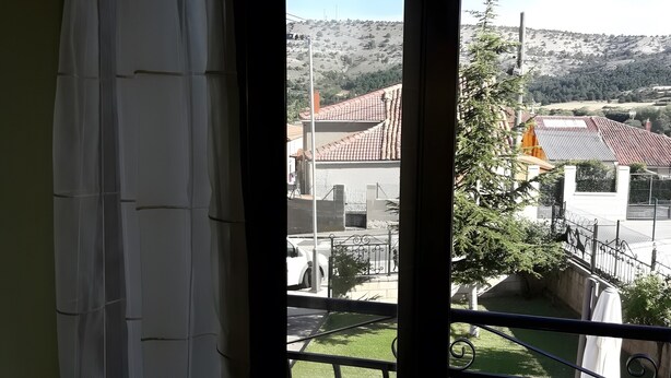 A balcony with a metal railing, a view of a residential area with houses and a hill in the background. - Apartment 'La Casa Nueva' with Balcony, Wi-Fi and Air Conditioning (Abejar)