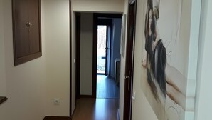 A hallway with a wooden floor, a door with a handle, and a wall-mounted artwork. - Apartment 'La Casa Nueva' with Balcony, Wi-Fi and Air Conditioning (Abejar)