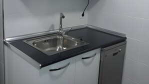 A kitchen with a stainless steel sink, a microwave, and white cabinets. - Apartment 'La Casa Nueva' with Balcony, Wi-Fi and Air Conditioning (Abejar)
