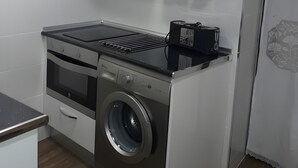A compact kitchen with a built-in oven, microwave, and a washing machine. - Apartment 'La Casa Nueva' with Balcony, Wi-Fi and Air Conditioning (Abejar)