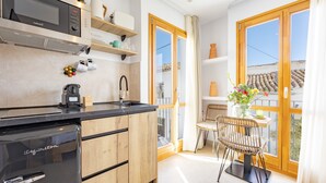 A modern kitchen with a built-in dishwasher, a coffee machine, and wooden cabinets. There is a dining area with a table and chairs, and a balcony with a view. - Room 'Altea  03' with Shared Pool, Wi-Fi and Air Conditioning (Altea)