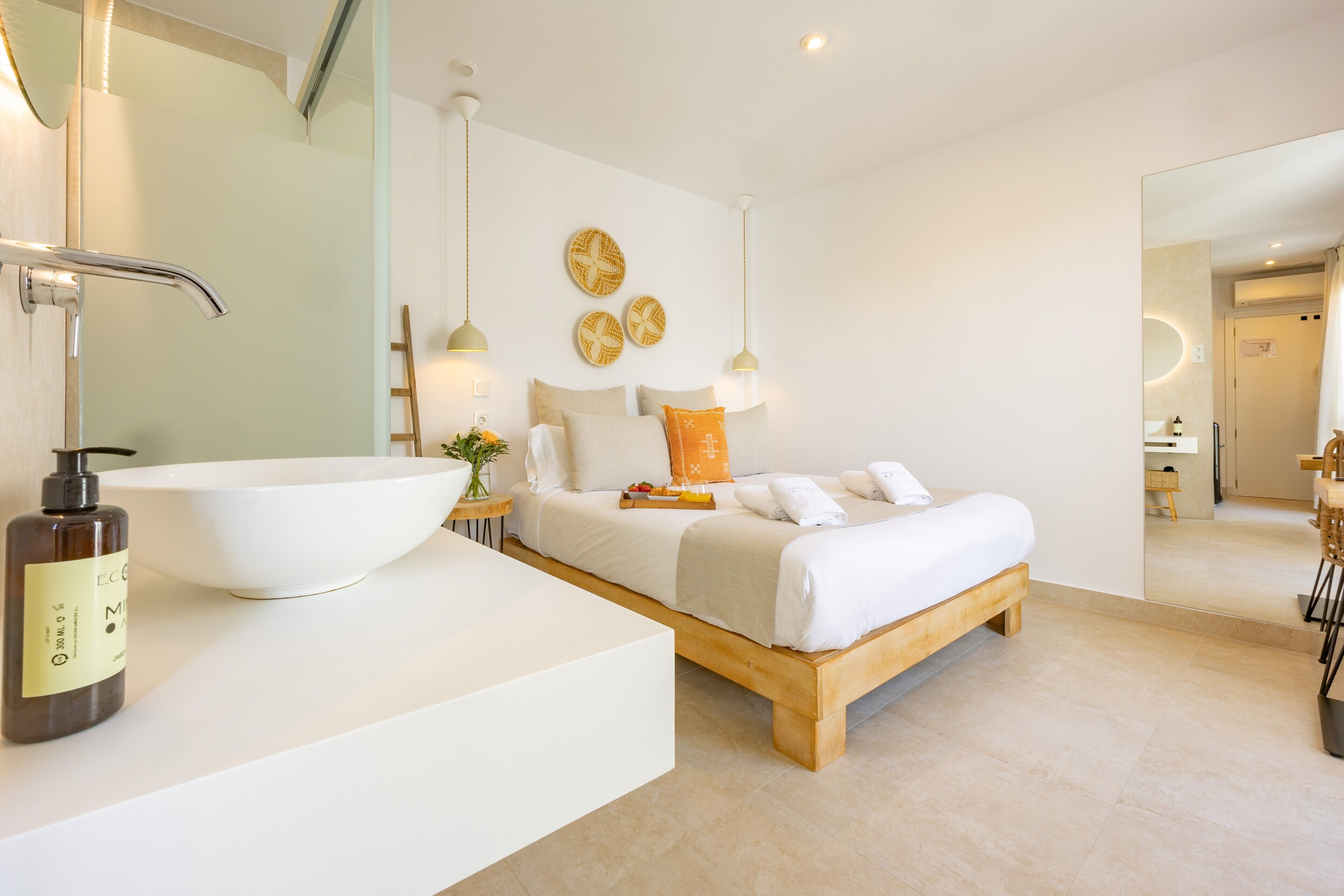 Een moderne slaapkamer met een groot wit wastafelmeubel, een houten bed en hanglampen.