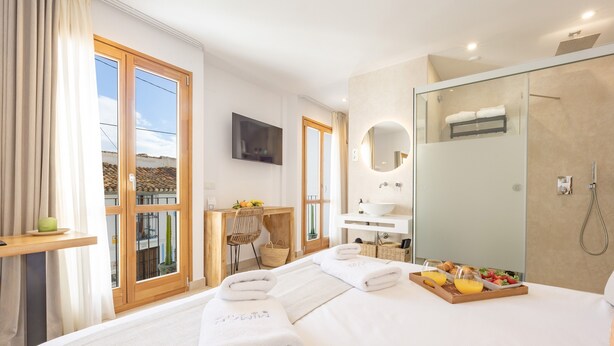 A hotel room with a large bed, a shower, a vanity, and a desk with a chair.