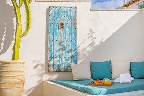 Una habitación con cama, una ventana con cortina azul, una planta en maceta y una bandeja con comida y bebidas.