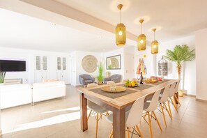 Un espace de salle à manger moderne avec une table en bois, des chaises et des lampes suspendues.