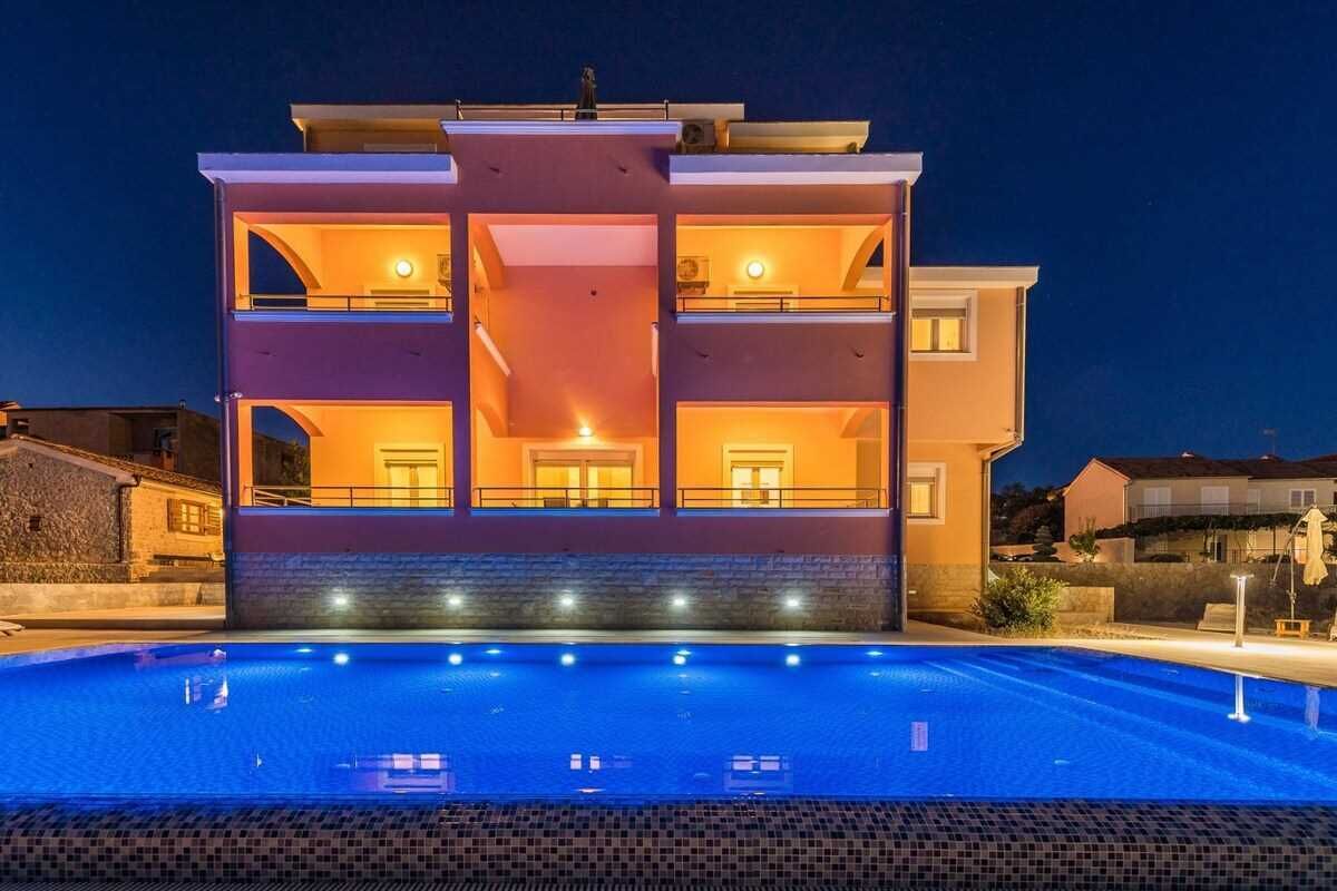 Un edificio de varios pisos con una piscina delantera.