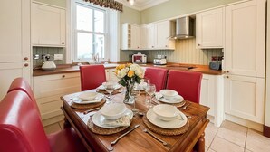 A dining area with a wooden table set for four, surrounded by red chairs. - 3 bedroom accommodation in Portpatrick, near Stranraer (Portpatrick, near Stranraer)