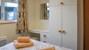 A bedroom with a bed, a wardrobe, and a window with curtains. - 2 bedroom accommodation in Brundall (Brundall)