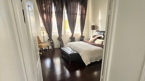 Un dormitorio con una cama grande, una mesita de noche, una silla y un escritorio.