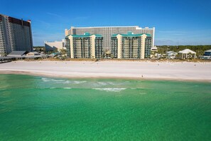 Un hotel frente a la playa con varias edificaciones, una playa de arena y agua turquesa cristalina.
