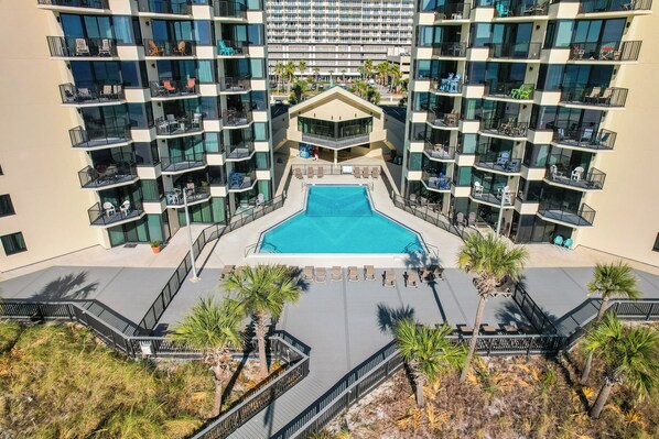 Un hotel moderno con piscina central, varios balcones y vistas de los edificios circundantes.